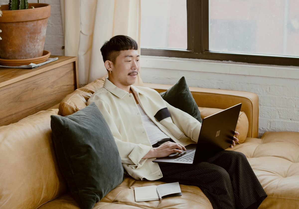 Man sitting on a couch using a laptop in a cozy living room.