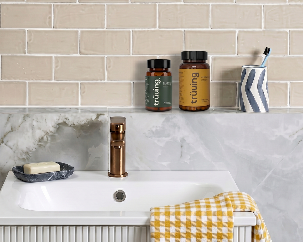 Bathroom counter with sink, toiletries, and a yellow checkered towel against a tiled wall.